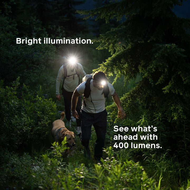 Two people and a dog hiking in the dark with headlamps, text highlighting 400 lumen brightness.