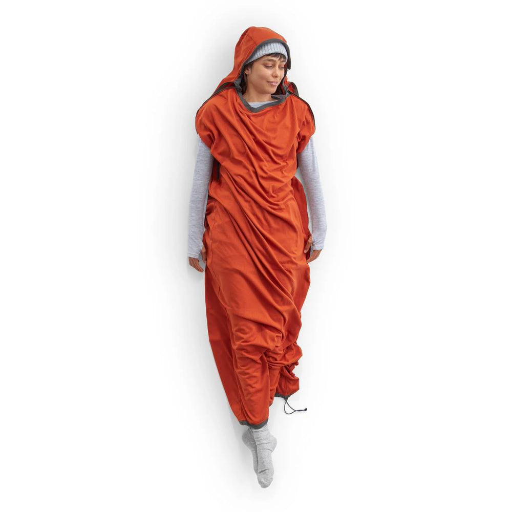 Women lying on a white background in a sleeping bag liner, with her arms and legs sticking out