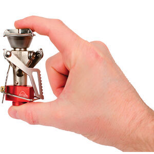 Hand holding a small red and silver camping stove against a white background