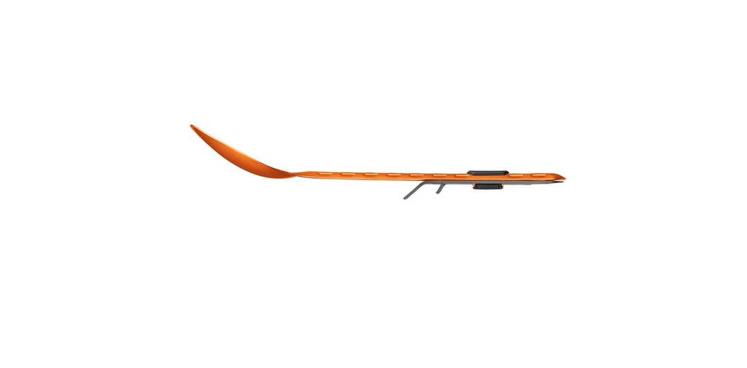 A long, narrow orange spork with a black handle and gray tip, shown in profile against a solid white background.