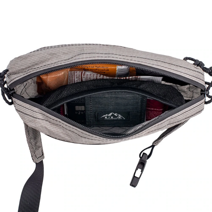 An open gray and black checkered crossbody bag showing its interior storage compartments, zipper, and a black zippered pouch with a visible logo.