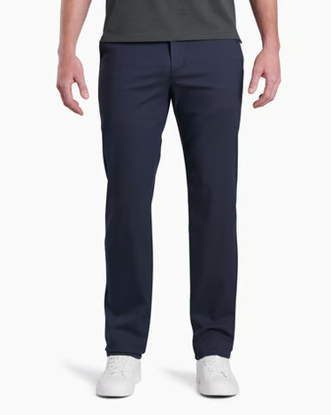 A man wearing navy blue straight-leg dress pants, a dark gray t-shirt, and white sneakers, shown from the waist down against a plain white background.