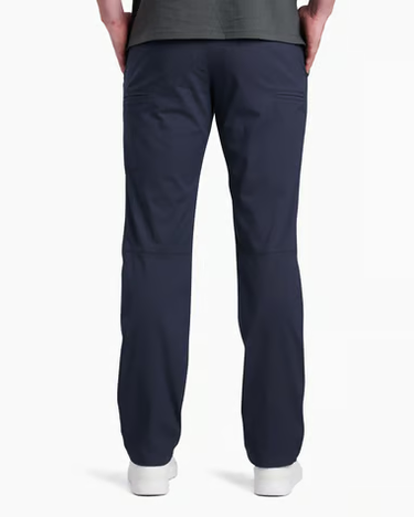 Rear view of a person wearing dark navy scrub pants with a dark gray top and white shoes, shown against a plain white studio background.