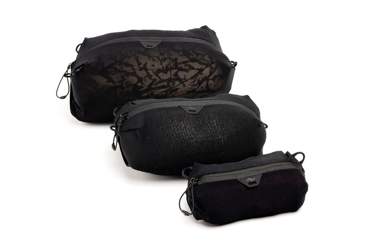 Three black mesh packing cubes of different sizes arranged diagonally on a white background.