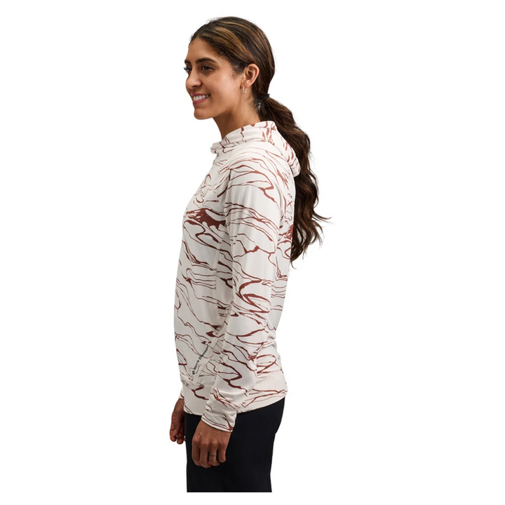 A woman shown in side profile wearing a hooded long-sleeve top with an abstract marbled pattern in brown and off-white, paired with dark pants, against a plain white background.