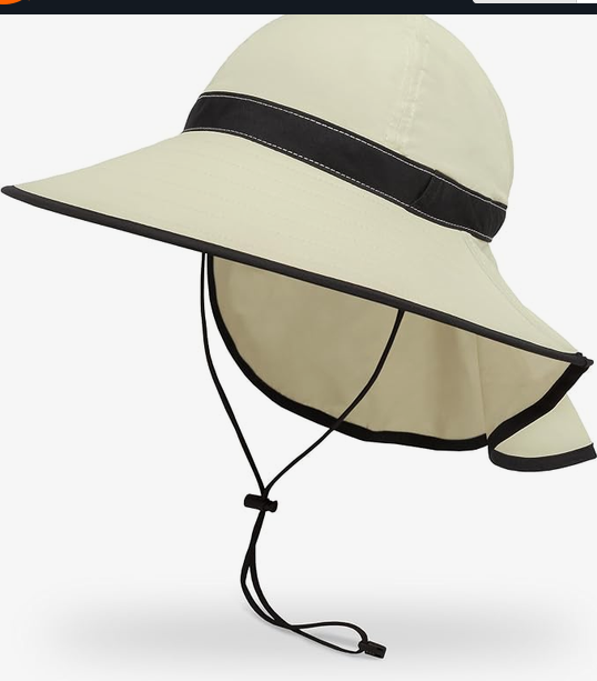 A light beige wide-brim sun hat with a black band and trim, featuring a chin strap, shown against a plain white background.