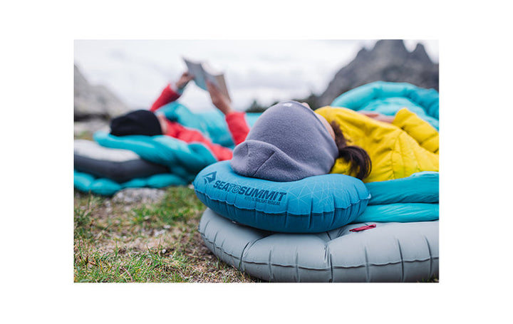Two people sleeping on the ground on sleeping mats with hiking pillows