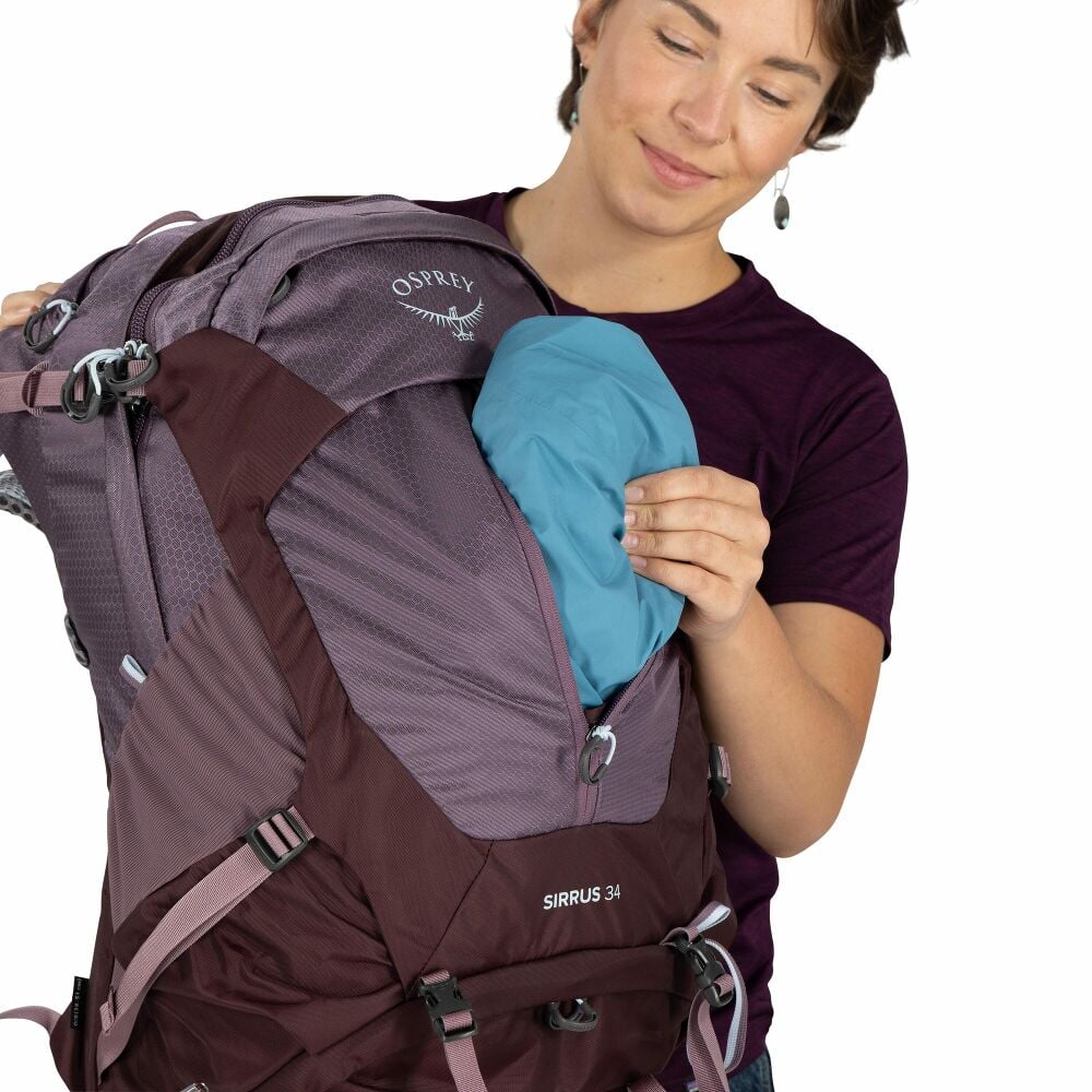 Person packing a purple backpack on a white background