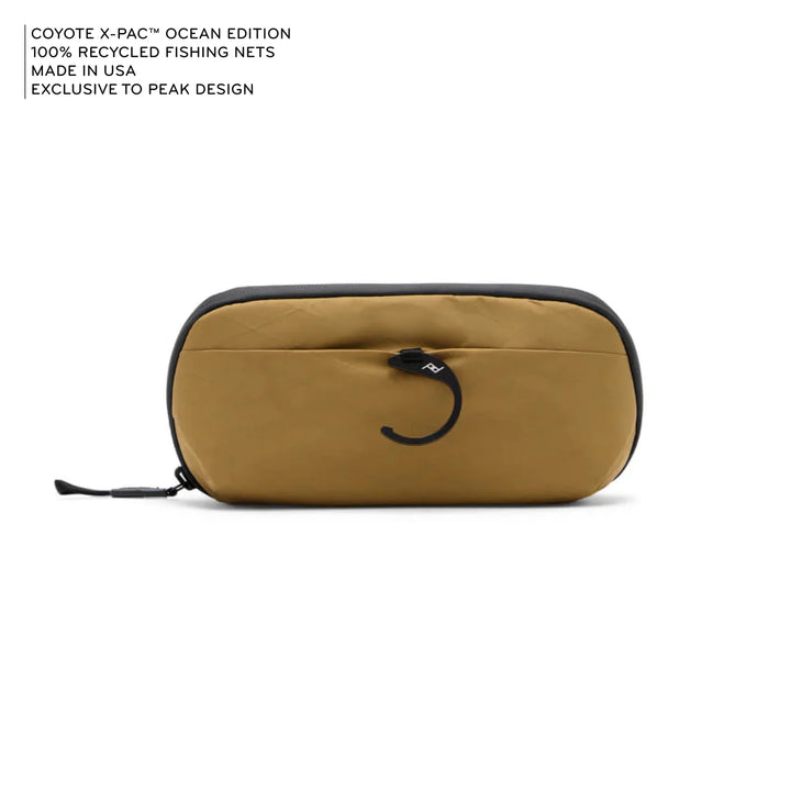 Beige carrying case with black zipper on a white background, featuring text about recycled fishing nets and Peak Design.