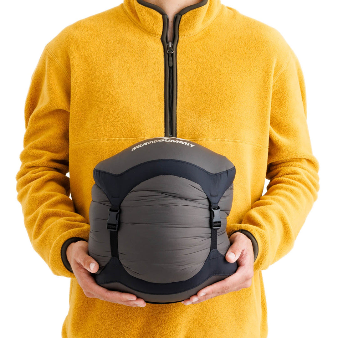 Person holding a sleeping bag in grey compression sack