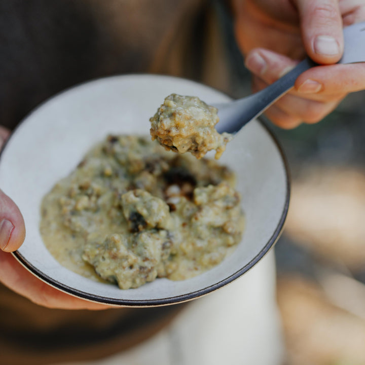 Person holding a bowl of food with a spoon