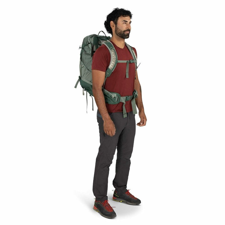 Man wearing a green hiking backpack on a white background