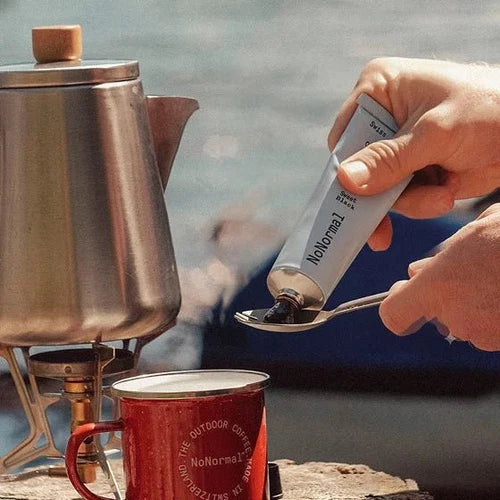 Person using a spoon to scoop coffee from a container labeled &