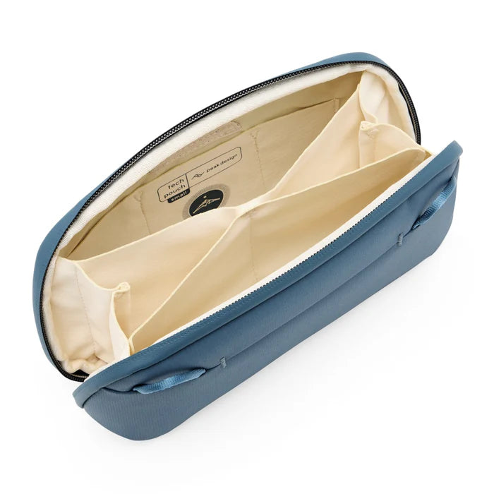 Inside of blue accessory pouch with beige interior and different pockets for organization on a white background