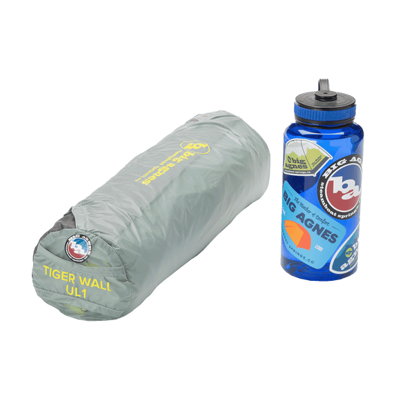 Grey roll up storage sack next to a 1L water bottle with Big Agnes stickers