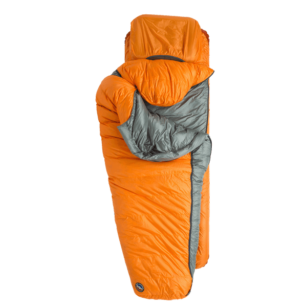 Orange sleeping bag and mat, bag folded forwarded to show a hiking pillow in a pocket under the head