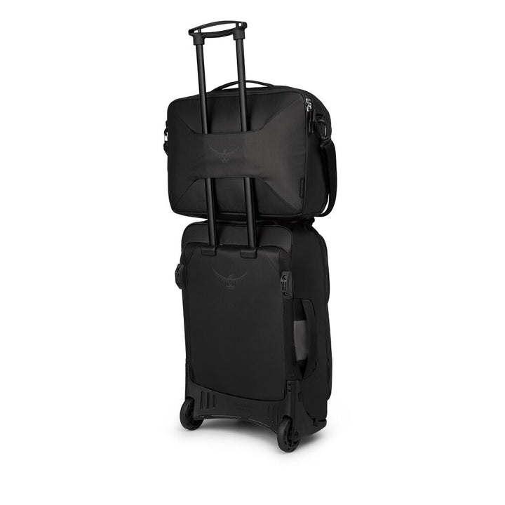 A black Osprey travel bag set featuring a softside suitcase with an extended telescoping handle and a matching laptop bag stacked on top, shown against a plain white background.
