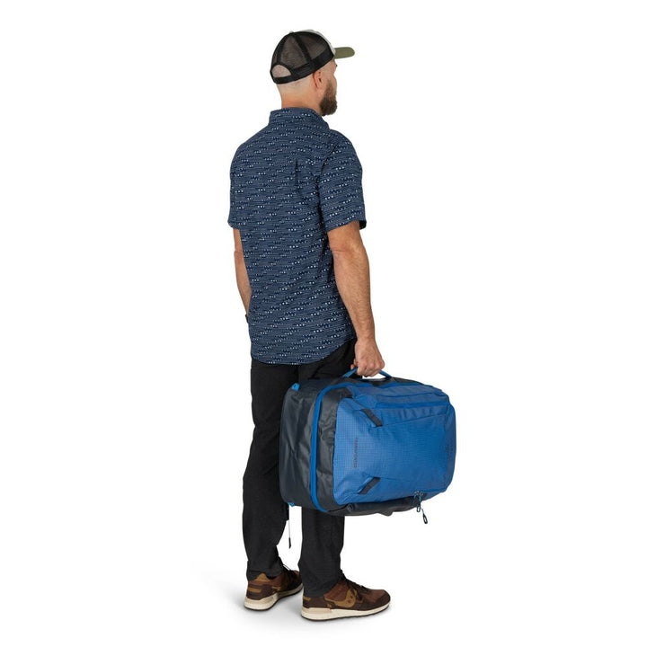 Man carrying a blue duffel bag on a white background