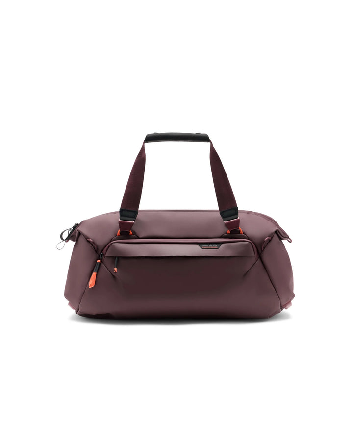 A dark burgundy nylon duffel bag with dual top handles, a top zip closure, and a front zippered pocket, shown on a plain white background.