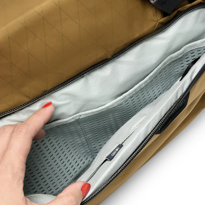 Open brown bag with gray interior and hand holding it