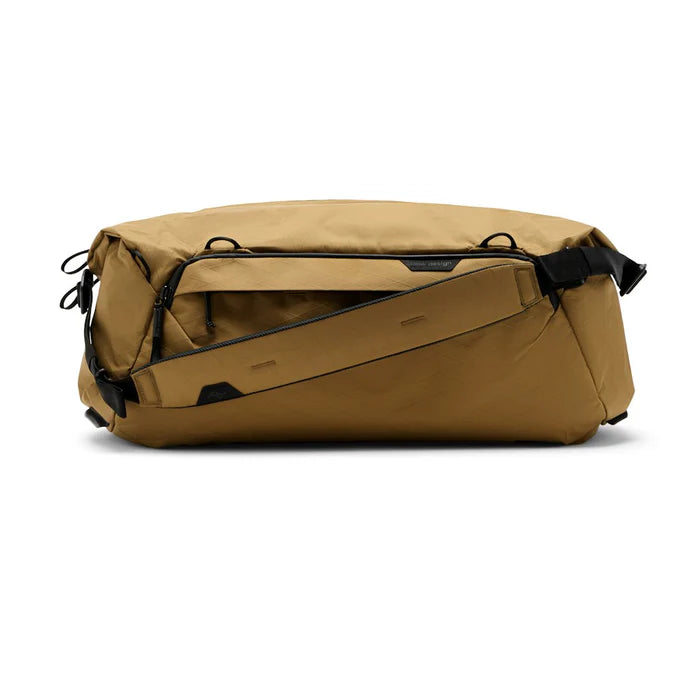 Tan duffel bag with black straps on a white background