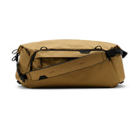 Tan duffel bag with black straps on a white background
