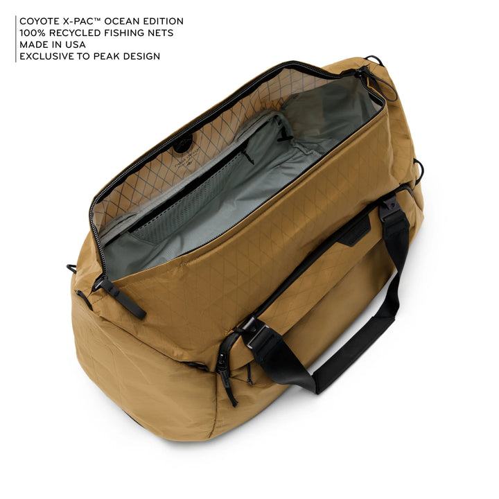 Brown duffel bag with black straps on a white background, featuring text about recycled fishing nets and USA manufacturing.