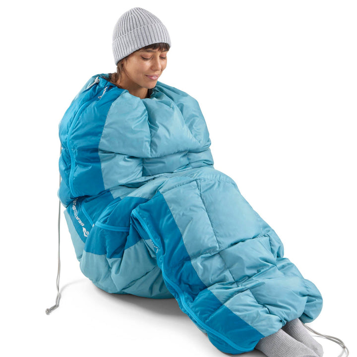 Woman in a blue sleeping bag with her feet sticking out the bottom