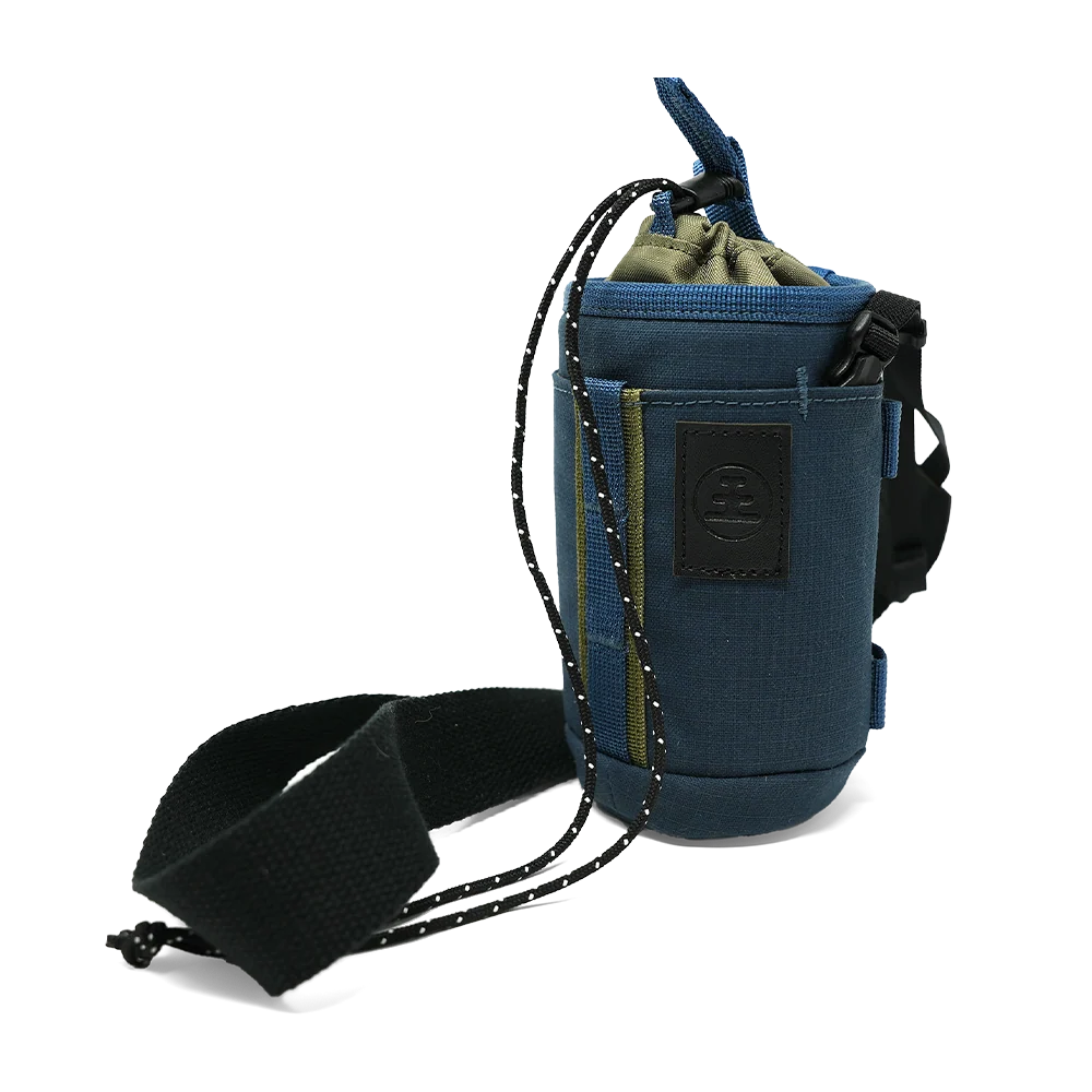 A blue drawstring pouch with a black adjustable strap and a black logo patch on the front, shown on a plain white background.