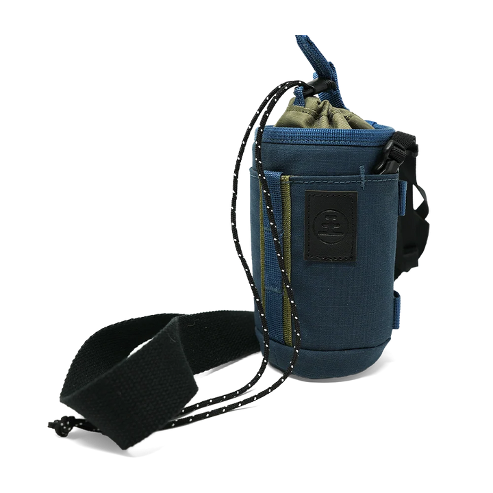A blue drawstring pouch with a black adjustable strap and a black logo patch on the front, shown on a plain white background.