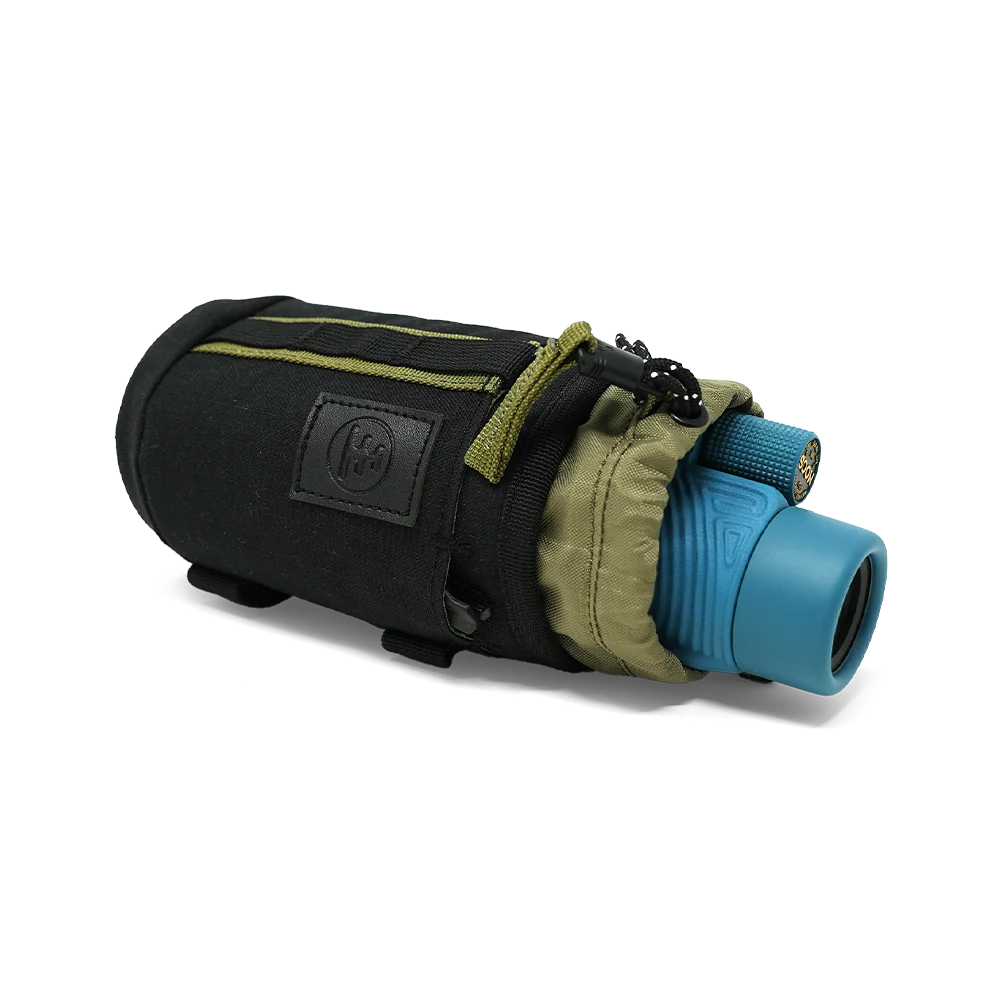 A black monocular sleeve with olive green accents, shown holding a blue monocular. The sleeve features a black logo patch on the front and a zippered closure, photographed on a clean white background.