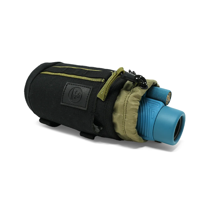 A black monocular sleeve with olive green accents, shown holding a blue monocular. The sleeve features a black logo patch on the front and a zippered closure, photographed on a clean white background.