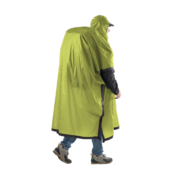 Person walking a lime green rain poncho over a large backpack