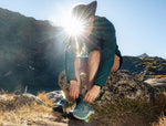 Person tying shoelaces outdoors with the sun shining into the lens over their shoulder