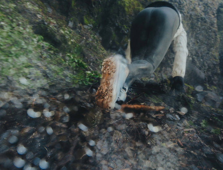 Person wearing pale blue running shoes runs up loose muddy terrain