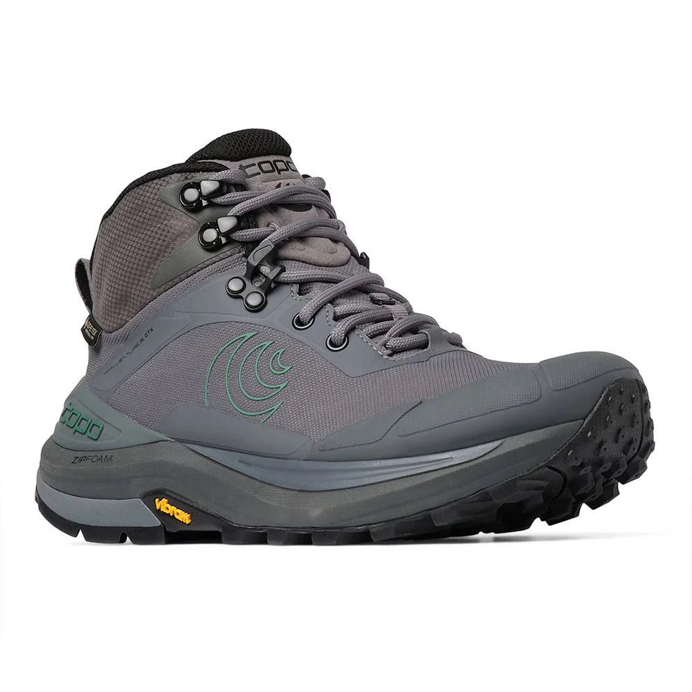 A gray mid-cut hiking boot with a black and gray Vibram sole, featuring a green wave logo on the side and a black tongue label with the brand name.