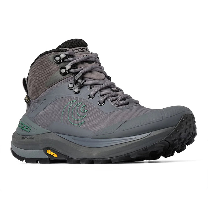A gray mid-cut hiking boot with a black and gray Vibram sole, featuring a green wave logo on the side and a black tongue label with the brand name.
