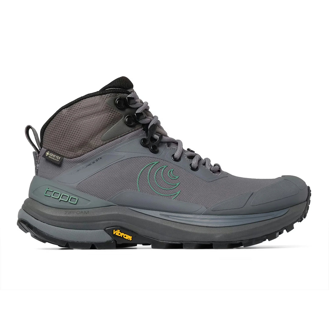 A gray mid-cut hiking boot with a dark gray sole, black laces, and a green circular logo on the side, shown against a plain white background.