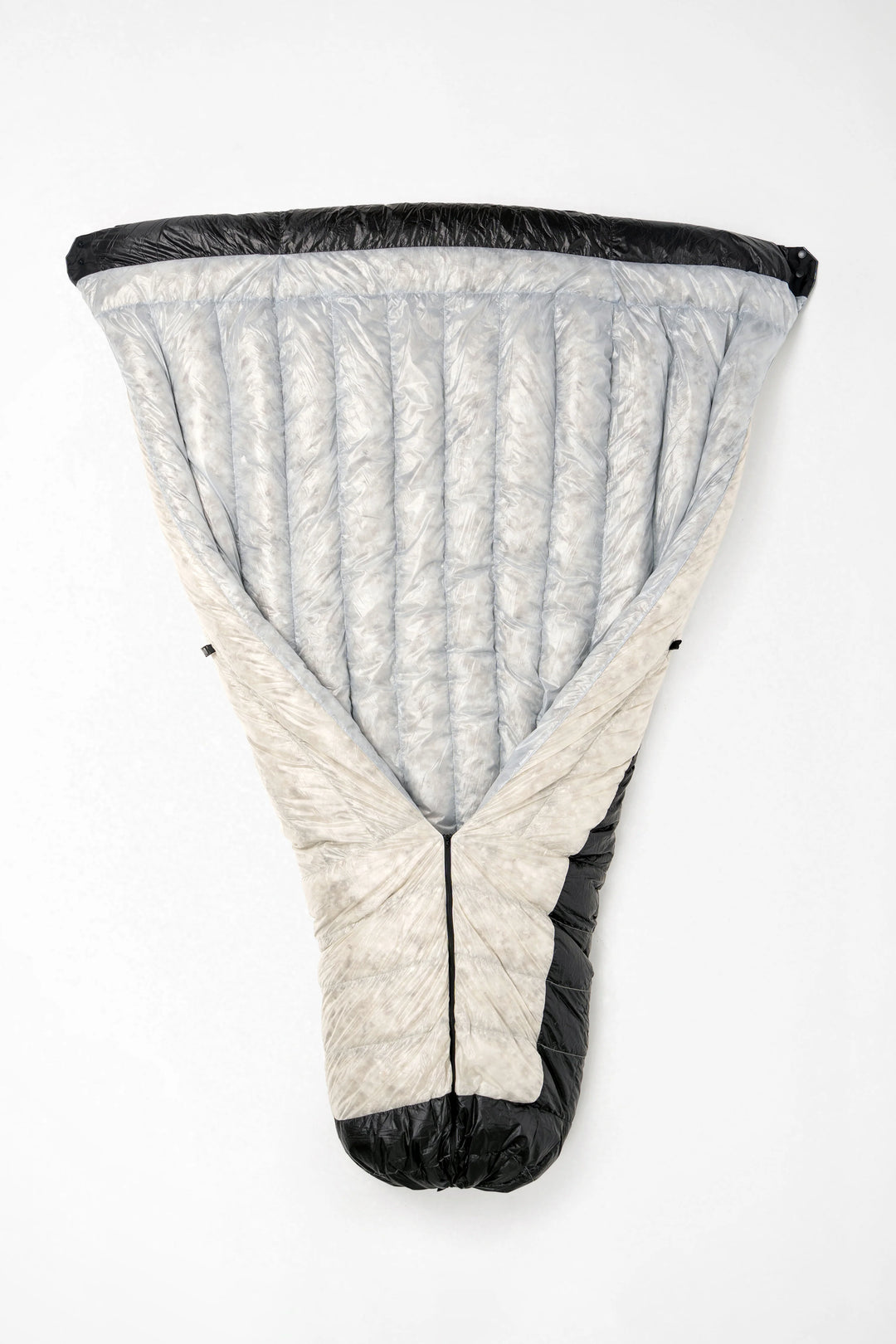 A light gray and off-white puffer sleeping bag with black trim, shown laid flat against a white background.