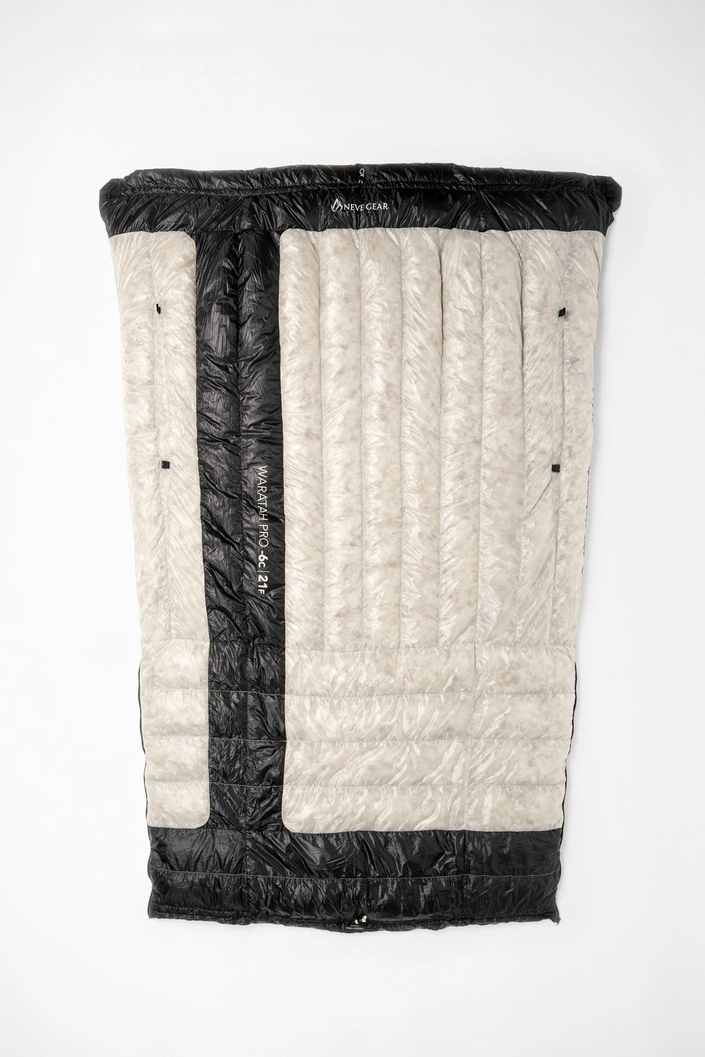 A folded sleeping bag or padded mat shown flat against a plain white background. The product has a light beige quilted outer panel with a vertical black center stripe and black top/bottom trim.