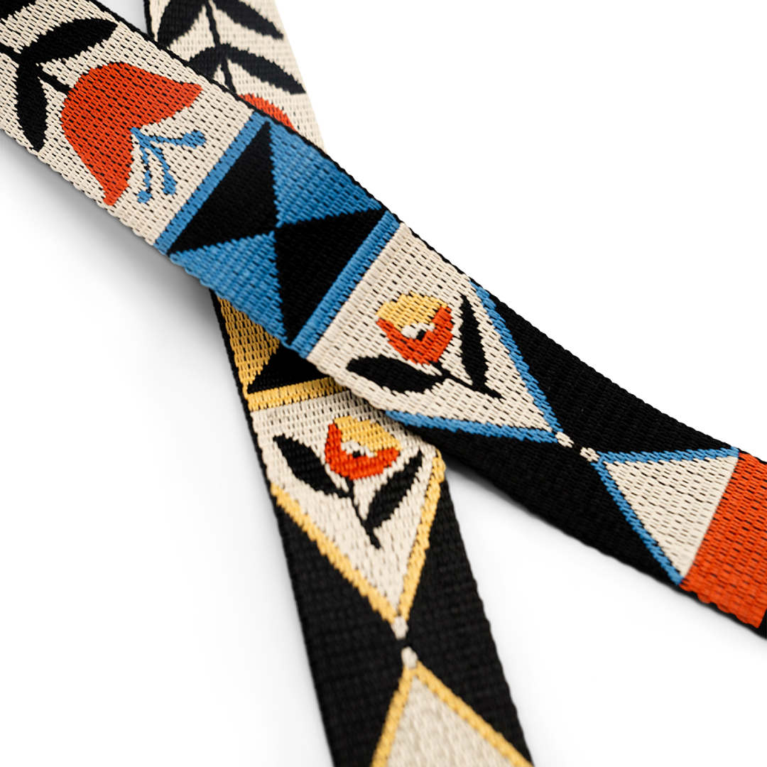Close-up of a camera strap with geometric floral patterns on a white background