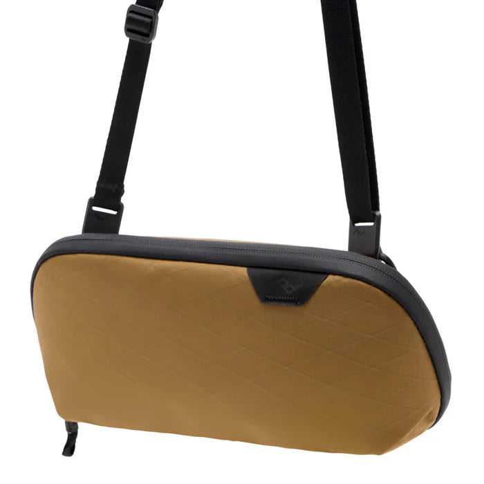 Tan accessory pouch with a black strap on a white background 
