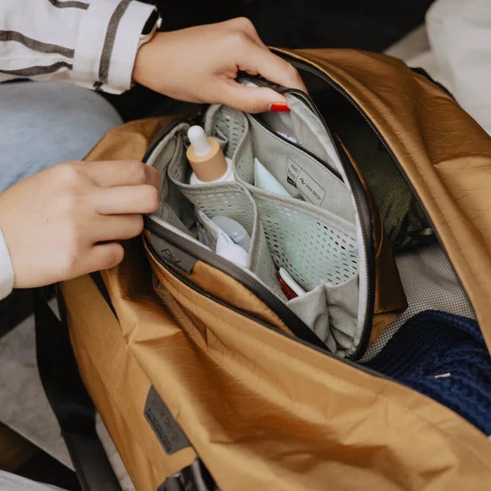 Person organizing items inside a brown backpack with a focus on travel or daily use.