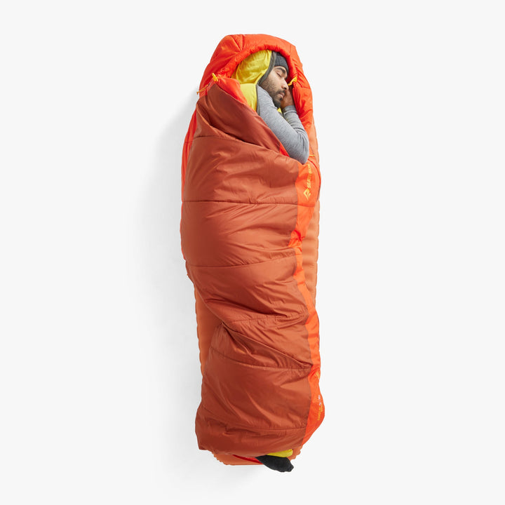 Person sleeping on their side in an orange sleeping bag on a white background