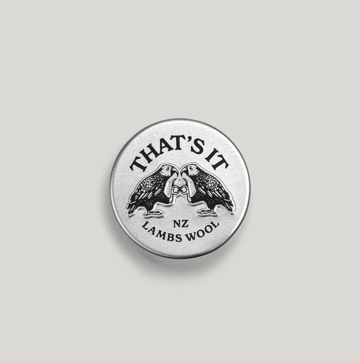 A round silver metal lid featuring a black engraved design of two facing birds with the text &