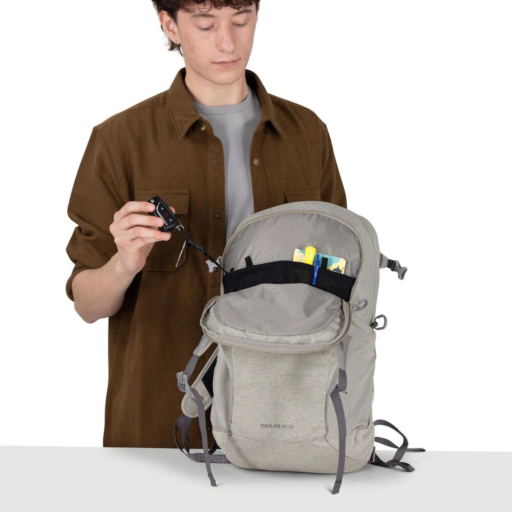 Person holding a gray backpack with items inside on a white background