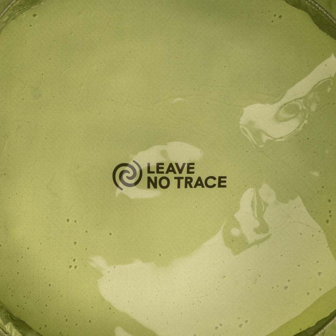 Bottom of a green nylon washing-up sink viewed through water showing "Leave no Trace" logo