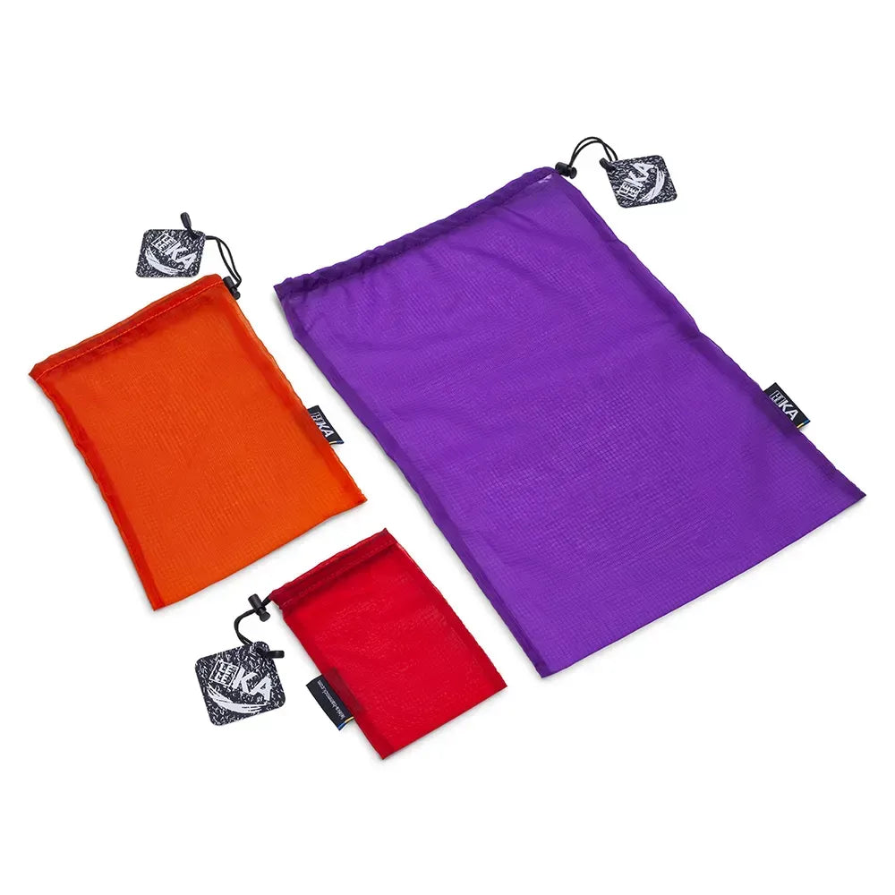 Three drawstring mesh pouches in orange, red, and purple, arranged diagonally on a white background. Each pouch has a black hanging tag with a white graphic logo.