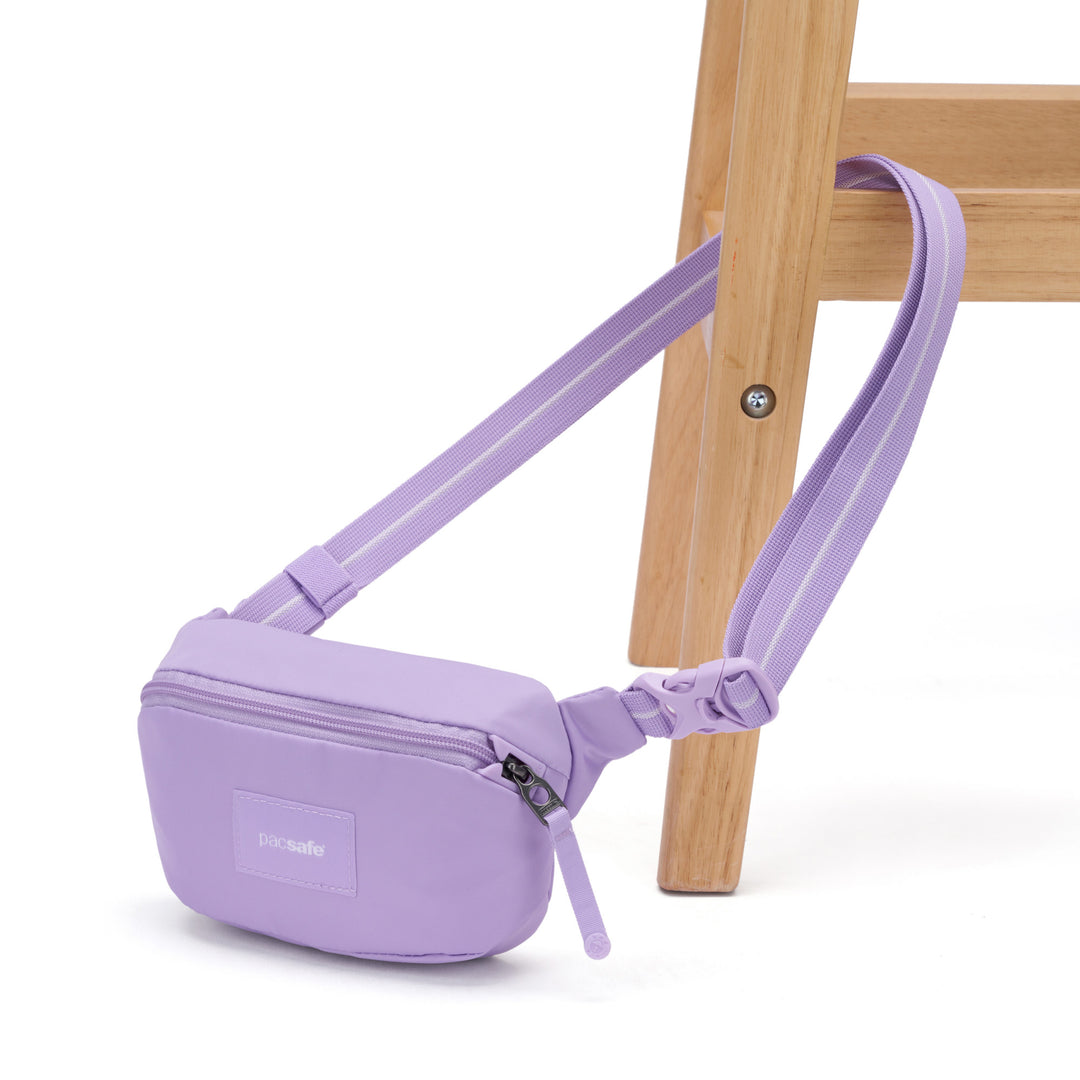 Pink sling bag with it strap clipped through the leg of a wooden chair