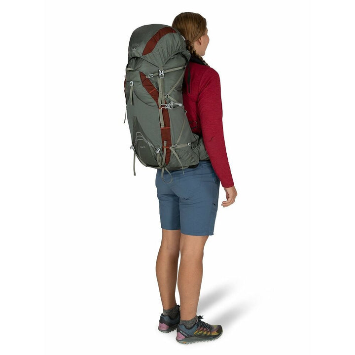 Person wearing a large grey hiking backpack on a white background